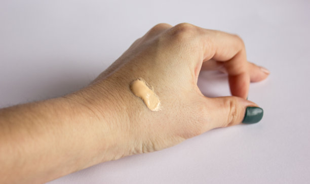 滴上一点色调粉底，在白色背景上涂上一层绿色指甲油。图片下载