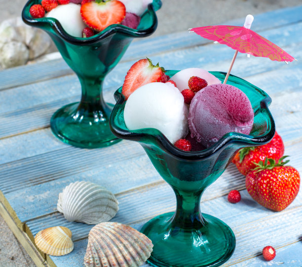 绿色的玻璃复古杯，水果雪糕球，蓝色的木板，沙滩上的贝壳图片下载