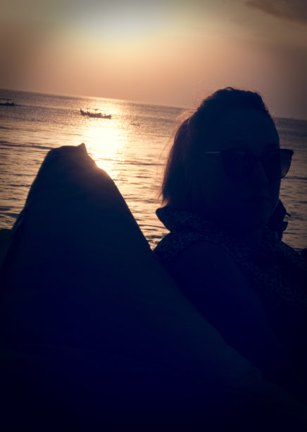 一个女人的侧面日落在库塔海滩在巴厘岛，印度尼西亚图片下载