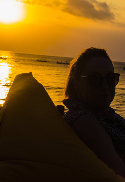 一个女人的侧面日落在库塔海滩在巴厘岛，印度尼西亚图片下载