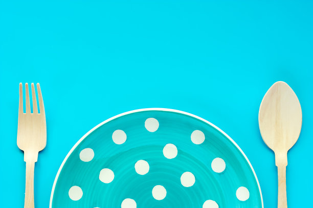 波尔卡点盘与木匙和叉在蓝色背景的器具和餐具概念图片下载
