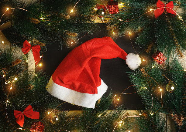 黑板上的圣诞帽被圣诞灯，装饰品和杉树枝包围图片下载