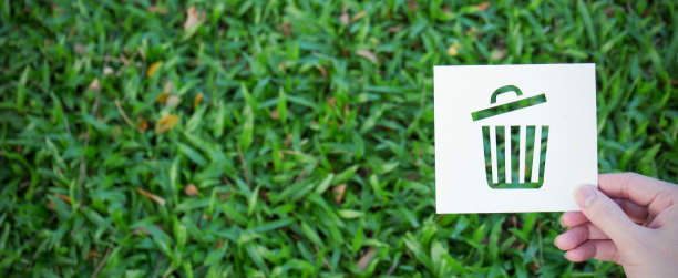 手握剪纸与bin形状的标志在绿色玻璃背景。标志符号背景横幅模板的环保理念。地球日图片下载