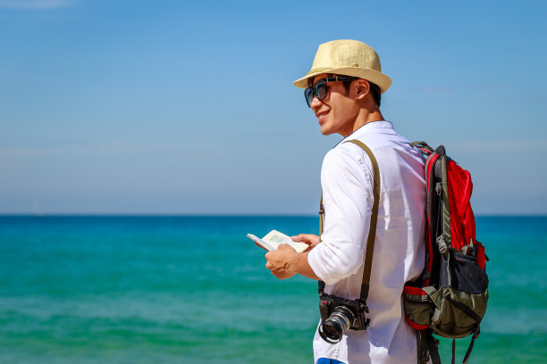 年轻的旅行亚洲男性背包客放松户外在热带海滩和海洋的背景，旅行和度假概念，复制空间图片下载