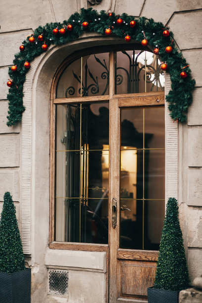 时尚的圣诞装饰品，花环灯和冷杉枝装饰窗户在欧洲城市街道。冬季城市中心的节日街道装饰和照明图片下载