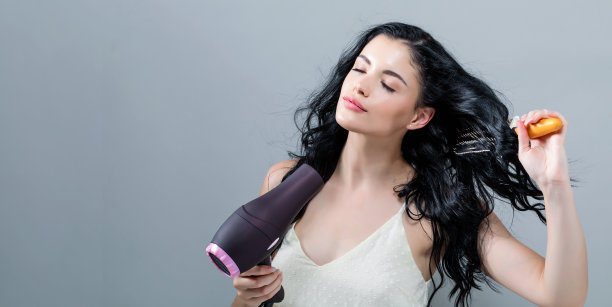 漂亮的年轻女人拿着吹风机图片下载