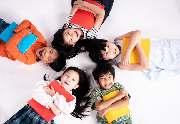 孩子们躺在一楼，手里拿着书，脸上带着微笑和快乐图片下载
