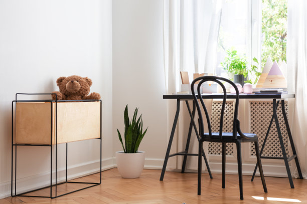 毛绒玩具在盒子旁边的椅子在书桌在青少年的房间内部有窗户和植物。真实的照片图片下载