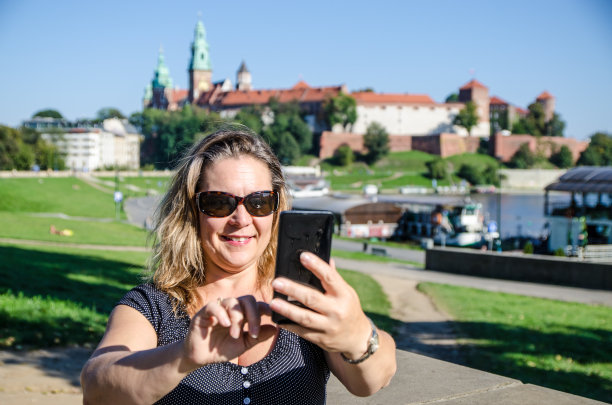 波兰克拉科夫，一名女子在夏日与维斯瓦拉河和瓦维尔大教堂自拍图片下载