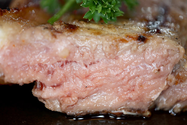 特写低角度照片优质t骨牛肉中熟牛排与黑胡椒在黑色盘子的背景，食物的概念。图片下载