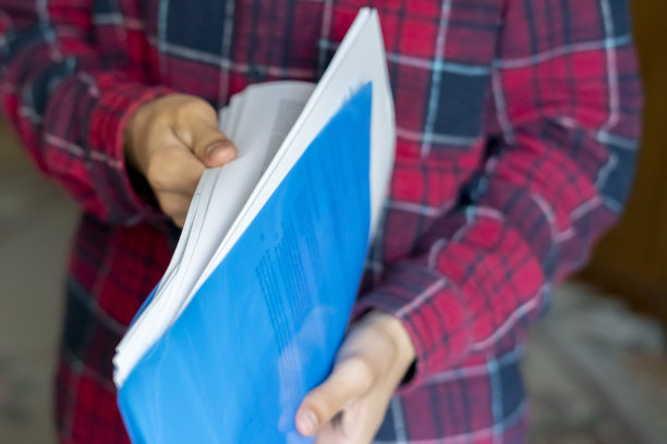 双手紧握蓝色文件夹，里面有文件，合同表图片下载