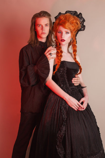 穿着万圣节服装的哥特式夫妇。苍白的吸血鬼穿着文艺复兴时期的裙子。万圣节派对的哥特式服装。亲爱的情侣在黑暗中。穿着文艺复兴服装的红头发女人。爱人在爱。图片下载