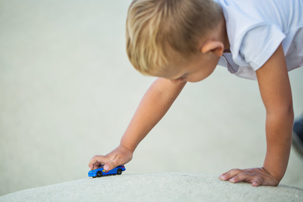 一个小男孩在玩跑车模型图片下载