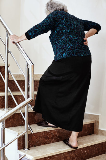 老妇人扶着楼梯扶手走上楼梯图片下载