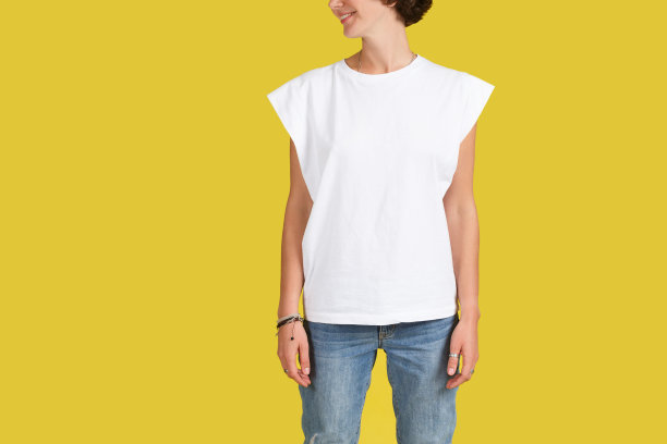 工作室拍摄的照片是一个穿着超大号白色t恤的年轻女性，在室内空白的黄色墙壁上摆姿势，墙上有你的文字或广告内容的拷贝空间图片下载