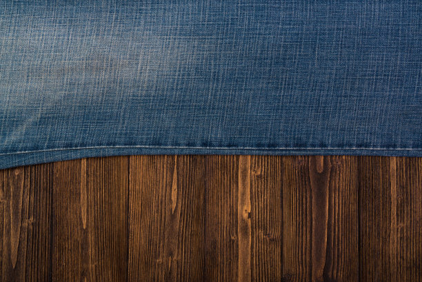 磨损牛仔裤或蓝色牛仔裤牛仔收集在粗糙的深色木制桌子背景，顶部视图与拷贝空间，旧的时尚概念。图片下载