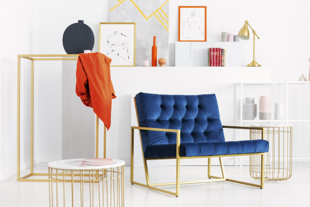 汽油蓝色的沙发在时尚的白色客厅中间，配有金色的配件和许多艺术品，真实的照片图片下载