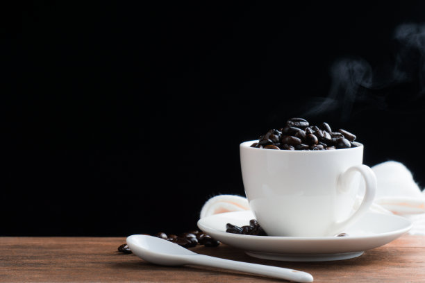 用白色陶瓷杯烘焙咖啡豆。咖啡豆富含抗氧化剂。咖啡中的咖啡因可以刺激新的皮肤细胞。图片下载