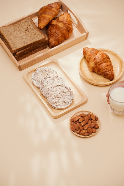 面包，小圆面包，牛奶，杏仁和新鲜牛奶的照片在桌子上与肤色背景。早餐准备，日常用品。图片下载