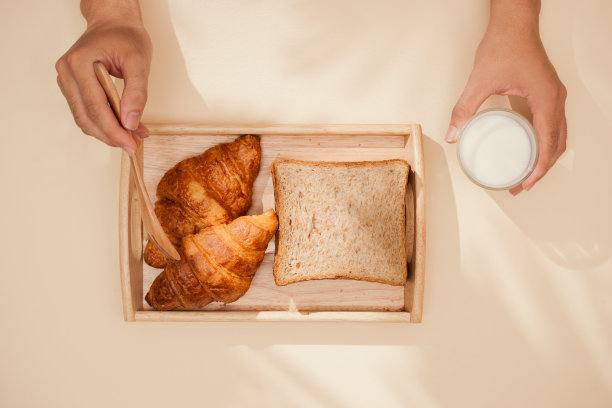 面包，小圆面包，牛奶，杏仁和新鲜牛奶的照片在桌子上与肤色背景。早餐准备，日常用品。图片下载