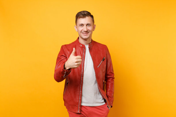 肖像时尚微笑帅气的年轻人25-30岁身穿红色皮夹克，t恤孤立地站在明亮的趋势黄色背景上。人真诚情感生活理念。广告区域。图片下载