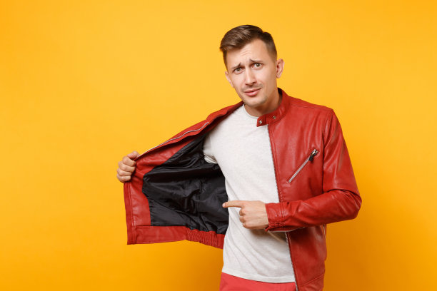 肖像时尚震惊了25-30岁帅气的年轻人身穿红色皮夹克、t恤孤立地站在明亮的趋势黄色背景上。人真诚情感生活理念。广告面积图片下载