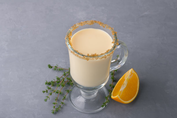 在灰色背景的玻璃杯中加入百里香和橙子自制蛋酒图片下载