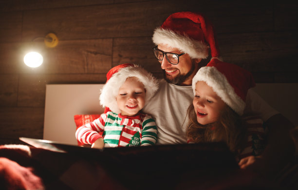 圣诞快乐!家里的父亲在孩子上床睡觉前给他们读书图片下载