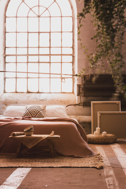 一个舒适的卧室内部的工业窗户，有一张床，桌子，框架和散热器。真实的照片图片下载