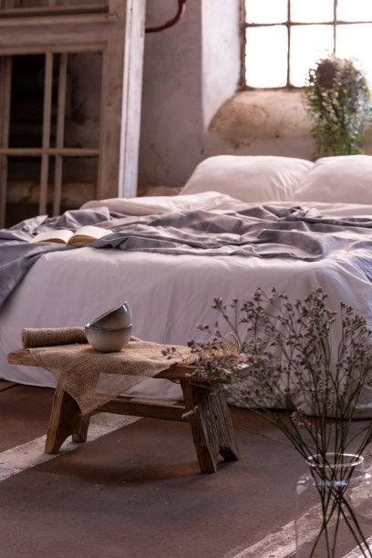 卧室里的花瓶里放着花，床前放着小桌子。真实的照片图片下载