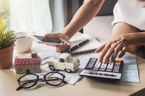 年轻女子在家里的客厅里用智能手机查看账单、税收、银行账户余额和计算开支图片下载