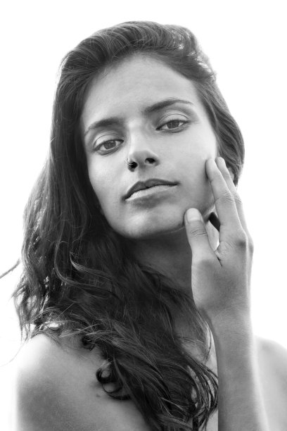 一个美丽的女孩的肖像温柔地触摸她的脸凝视着照相机，黑白图片下载