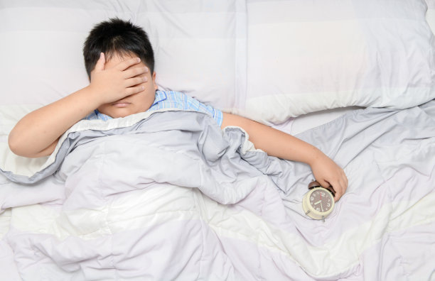 男孩因头痛躺在家里的床上图片下载