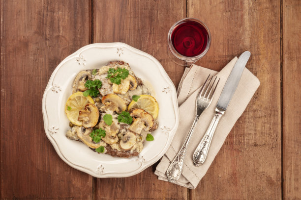 这张照片拍摄于一个深色的乡村木纹上，配以红酒、复古餐具和仿品空间，上面是意大利扇贝、小牛肉扇贝和蘑菇酱、柠檬和欧芹图片下载