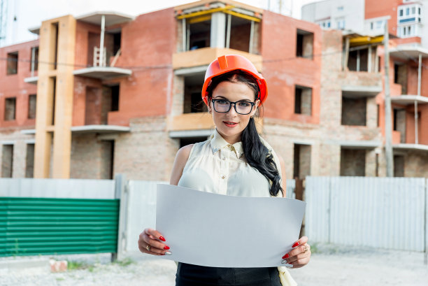 工地背景上的妇女正在检查蓝图图片下载