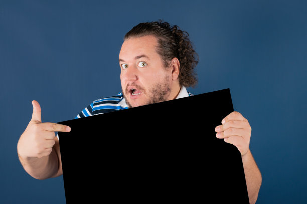 一个穿着亮条纹衬衫的滑稽胖子，手里拿着一块黑色的书写板图片下载