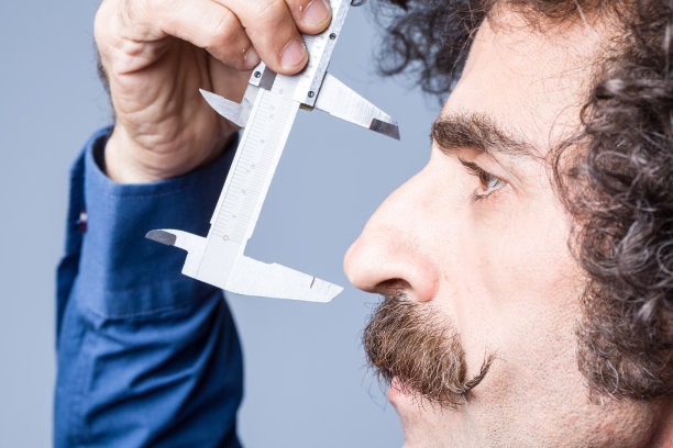 近距离的肖像成年男子测量他的鼻子图片下载