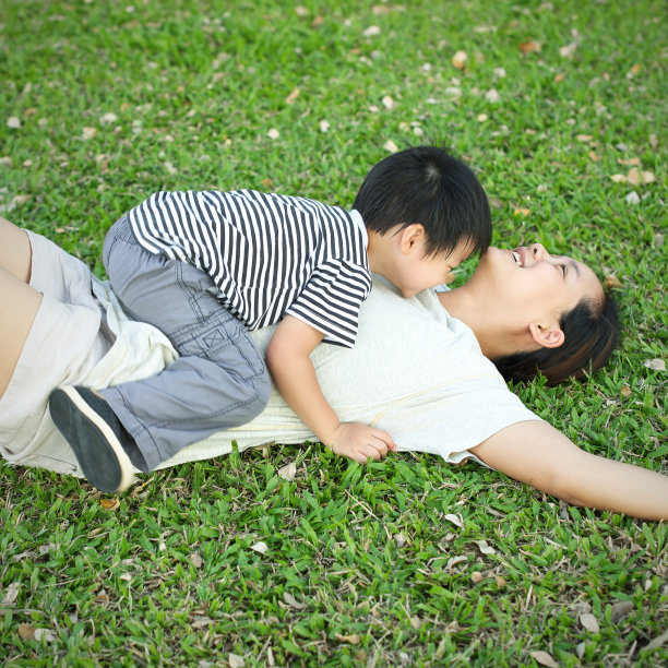 一个亚洲小孩躺在年轻母亲的草地上图片下载