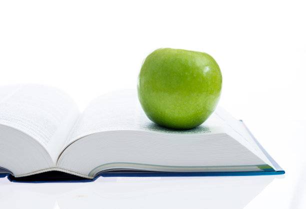 绿色的苹果和打开的书在白色的背景图片下载
