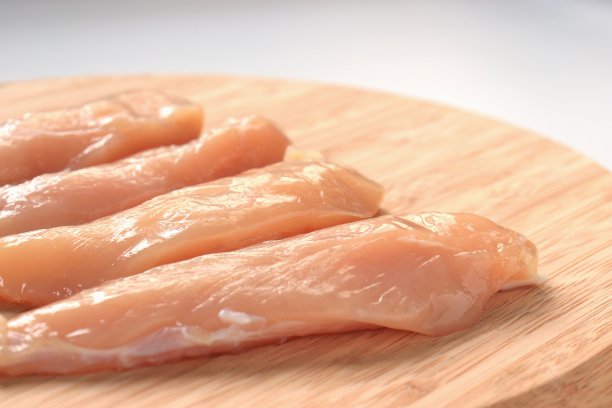 一块鸡肉放在木砧板上图片下载