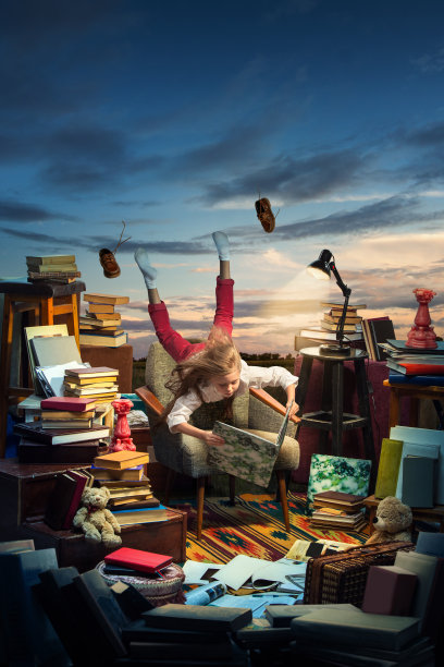 小女孩坐在打开的书上。童年的梦想、创造和教育理念。不知道的世界。抽象拼贴画图片下载