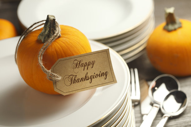 感恩节快乐标签挂在南瓜上，放在一堆盘子上图片下载