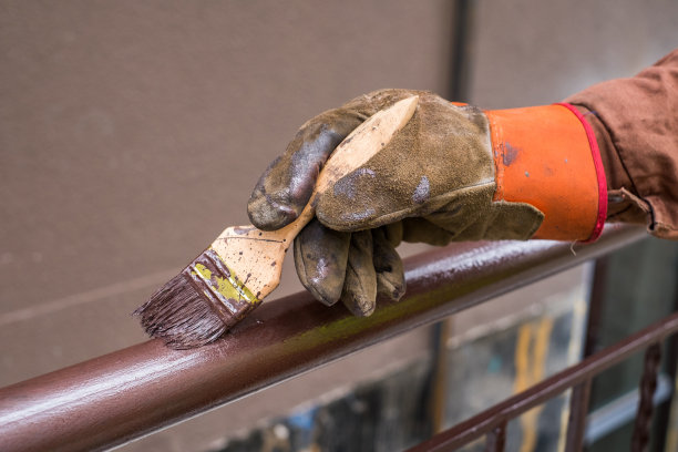 承包商的手用刷子刷着金属栏杆的结构。图片下载