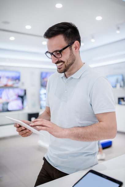 一个人站在科技店里试着平板电脑。图片下载