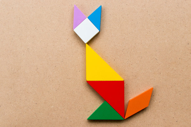 色彩七巧板拼图在坐猫形状的木头背景图片下载