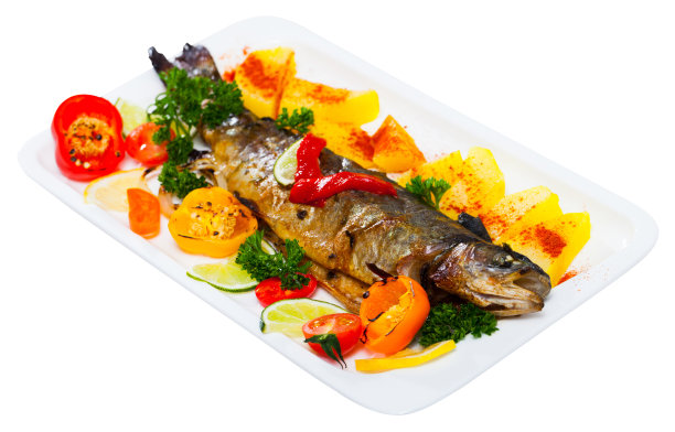 美味的烤整条鳟鱼配蔬菜，青菜和柠檬图片下载