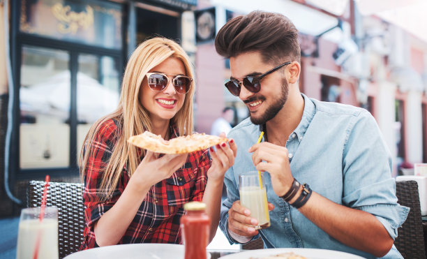 一对夫妇坐在咖啡馆里吃披萨。消费主义、食品、生活理念图片下载