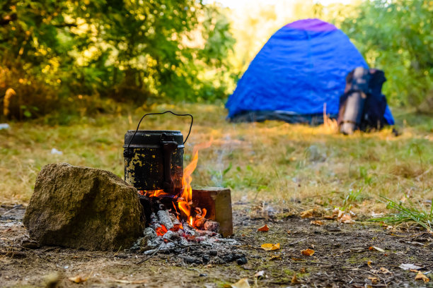 用水壶在篝火上煮食物。帐篷的背景图片下载