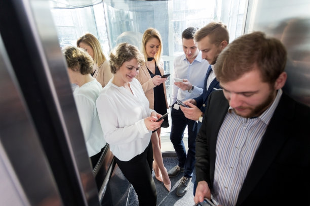 在玻璃电梯里用智能手机的商务人士图片下载