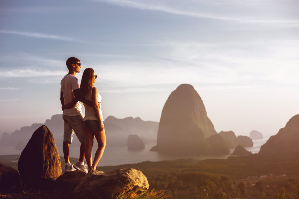 夫妇站在大岩石看日出日落海岛屿图片下载